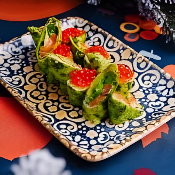 Green rolls filled with red caviar and salmon, served on a decorative blue and gold plate.