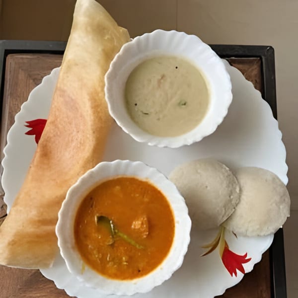 A Sri Balaji Indian meal with dosa, idli, sambar, and coconut chutney on a white plate.