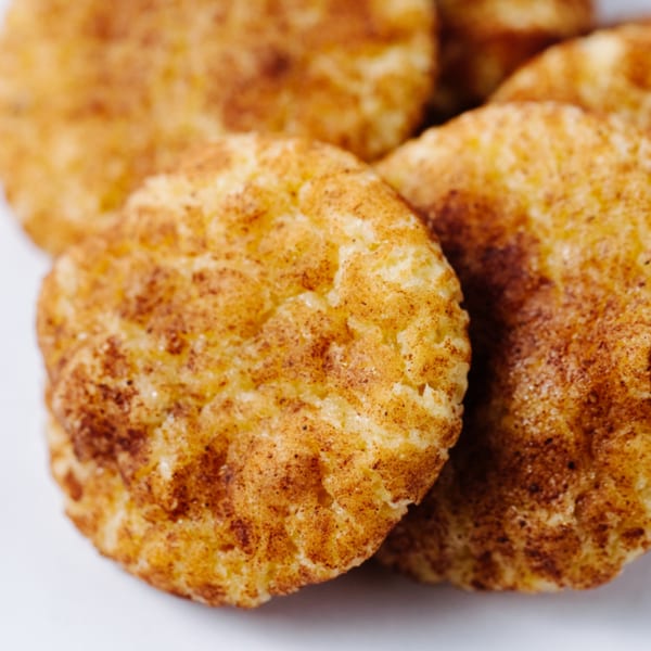 Close-up of several golden-brown Indian sweets, possibly cookies or pastries, dusted with spices.